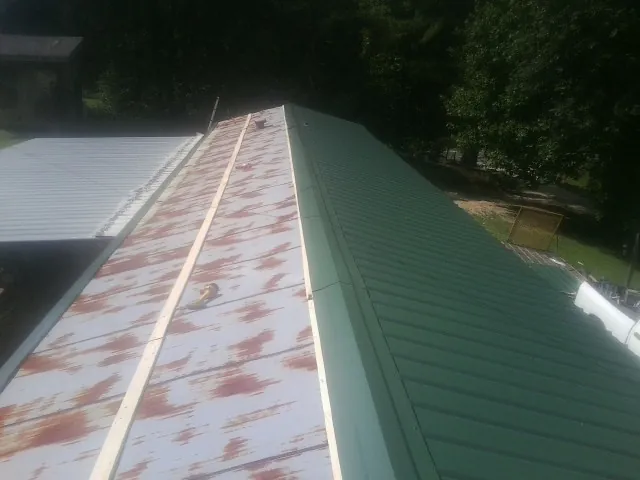 Old rusted panels beside newly installed green metal roofing — Wind Damage Roof Repair by Roofing Brothers in Port Republic